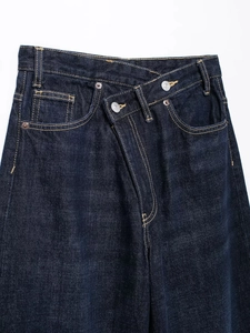 Vue détaillée du jean bleu foncé avec une taille croisée unique à double boutonnage