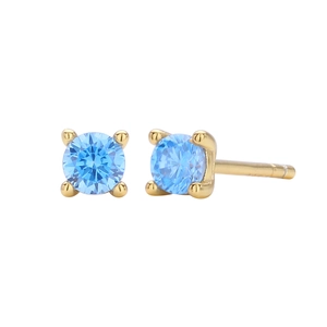 Macro detail of round light blue gemstone studs with gold four-prong setting