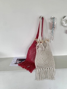 Detail of hand-woven straw shoulder bag with wooden ring handle and long bottom tassels