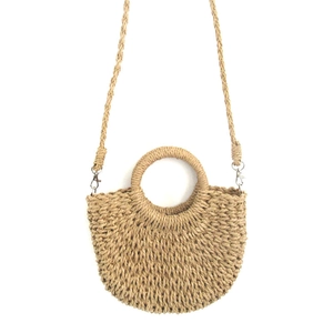 Detail of hand-woven straw tote bag with round handle and detachable shoulder strap