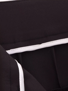 Detailed macro shot of fine stitching and pleated design on black high-waisted suit pants