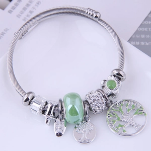 Silver tree of life cable bracelet with green beads and pavé charms on white tray