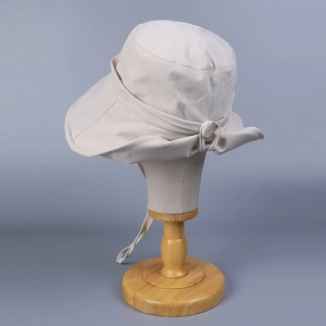 Close-up of beige wide-brim sun hat with button detail and adjustable wind lanyard