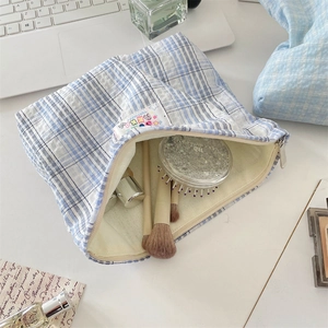 Dettaglio della borsa da trucco a quadretti blu con cerniera e accessori di bellezza