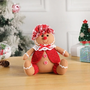Close-up of plush gingerbread man with red festive hat and lace bow on wooden table