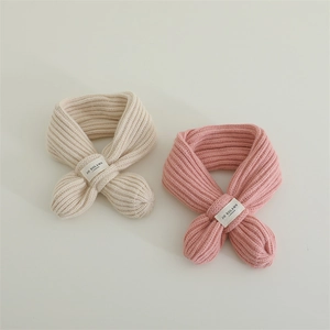 Detail of soft ribbed knit baby scarf with cross-over strap and designer label