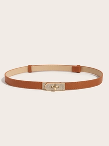 Detail of a slim brown lychee leather belt featuring a sparkling gold rhinestone lock buckle
