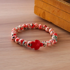 Detailed shot of a stone beaded bracelet featuring colorful spotted beads and a red turtle charm