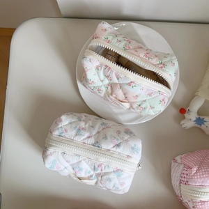 Detailed macro view of quilted floral makeup bags with pastel patterns and zip closures