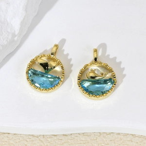 Gold-plated ocean whale and tail pendants with blue crystal on a white stone base