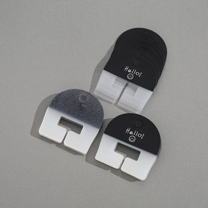 Detail of semi-circular black and gradient grey plastic hair clip packaging cards with Hello text