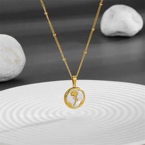 Detail of golden steel necklace featuring a square white shell rose pendant on stones