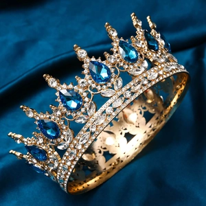 Detailed close-up of golden tiara with blue teardrop crystals on navy velvet
