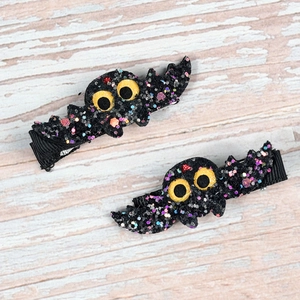 Detail of glittery black bat hair clips with yellow eyes for Halloween costume accessories