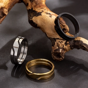 Anelli industriali in acciaio nero, argento e oro su espositore in legno materico