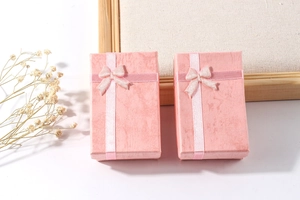 Pink paper jewelry gift box with textured surface and elegant bow ribbon detail