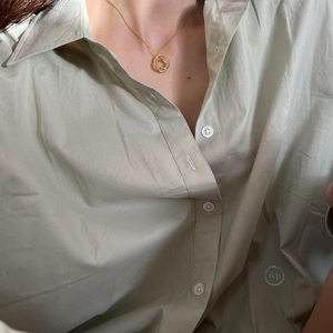 Close-up of a 925 silver golden oval interlocking pendant necklace on a model