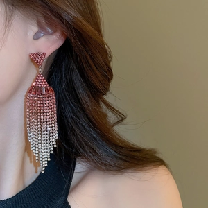 Detailed view of silver needle tassel earrings with pink gradient rhinestones on model