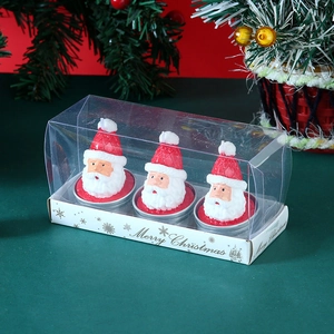 Detailed view of three Santa Claus candles in a gift box with pine and berry background