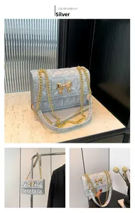Details der silbernen Stepptasche mit goldener Schleife und Metallkettenriemen