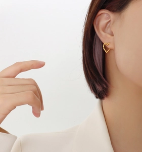 Close-up of beaded 18k gold heart earrings worn by a model in a minimalist style