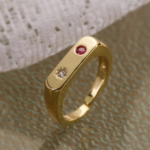 Macro shot of gold adjustable ring featuring a round red stone and star-set zircon