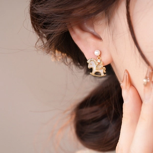 Detail of elegant rocking horse earrings with pearls and crystals on a model's ear