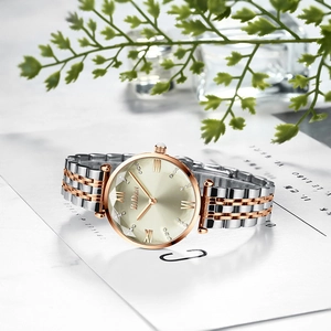 Detail of rose gold and silver watch dial with Roman numerals on marble background