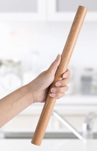 Detail of hand holding a seamless solid wood rolling pin showing natural grain and texture