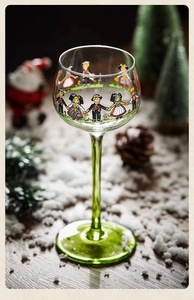 Detailed view of cocktail glass with green stem and festive traditional figure pattern