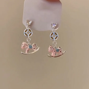 Detail of pink enamel rocking horse earrings with heart-shaped zircon studs