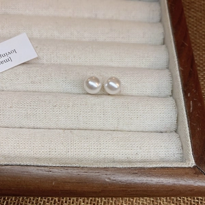 Detailed view of elegant white round pearl earrings set in a beige velvet jewelry organizer