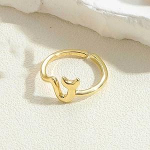 Detailed view of an adjustable 14K gold plated abstract flower ring on a stone texture