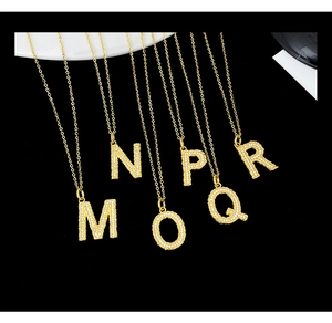 Macro shot of gold-plated alphabet necklaces M to R with sparkling zircon crystals