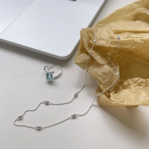 Detail view of a 925 sterling silver beaded necklace with an oval charm on vintage paper
