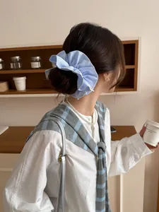 Detail of blue and white striped fabric scrunchie with ruffled texture on a model