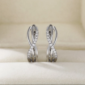 Macro shot of silver twisted hoop earrings with white zircon stones on a velvet jewelry box
