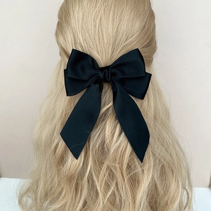 Elegant black bow hair clip for women in a minimalist fairy style worn on the back of the head