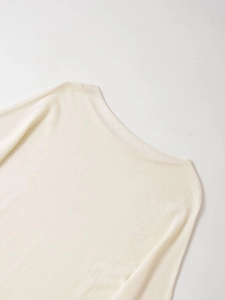 Close-up of cream white flat-knit sweater showing the boat neckline and soft fabric texture