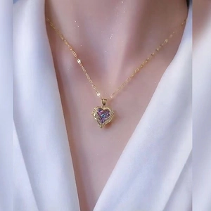 Elegant heart necklace with iridescent purple crystal and gold chain worn on neck