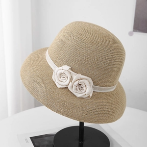 Détail d'un chapeau de paille tissé avec décorations de roses en tissu et rubans élégants