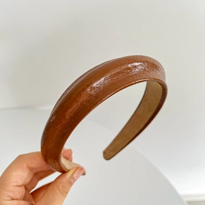 Close-up of brown faux leather headband with sponge padding and textured finish