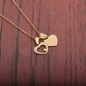 Detail showing two gold heart pendants with Love engraving on a wooden surface