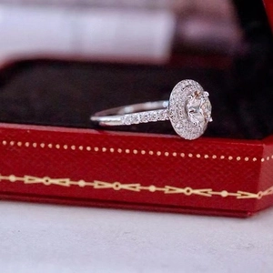 Detail of round halo engagement ring with pavé diamonds in a classic red jewelry box