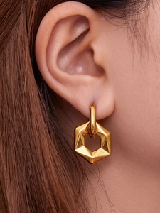 Detail of model wearing gold geometric hexagonal pendant earrings in minimalist style