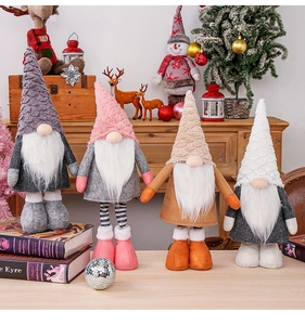 Set of four plush Christmas gnomes in grey and pink on a festive wooden surface