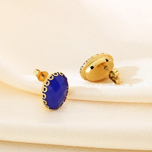 Oval blue gemstone stud earrings in gold vintage setting on beige silk fabric