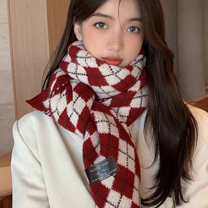 Close-up of a red and white argyle knit scarf with 100% acrylic fabric care label