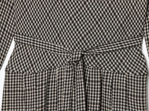 Detail of classic houndstooth dress featuring a waist tie knot and woven texture