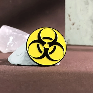 Macro view of a yellow metal biohazard symbol badge on a textured stone background